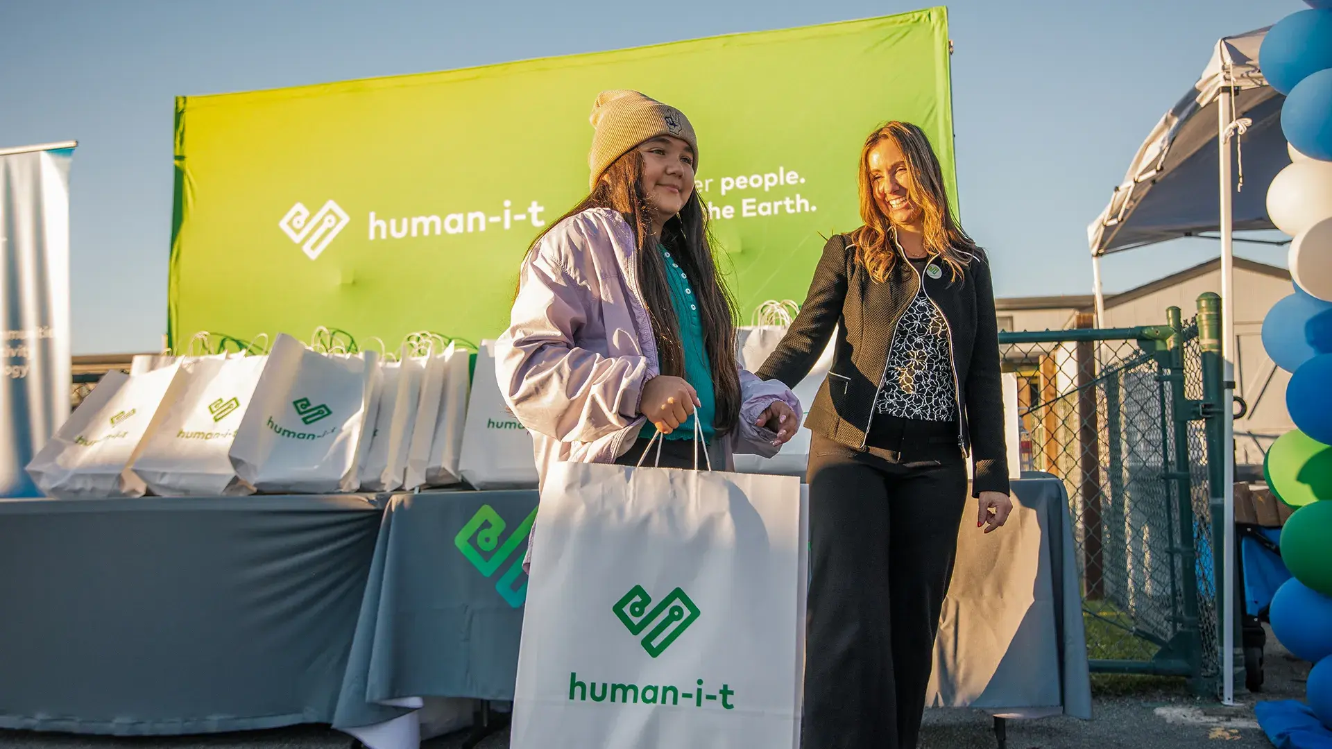 Image of two women carrying a tote bag with the Human-I-T logo