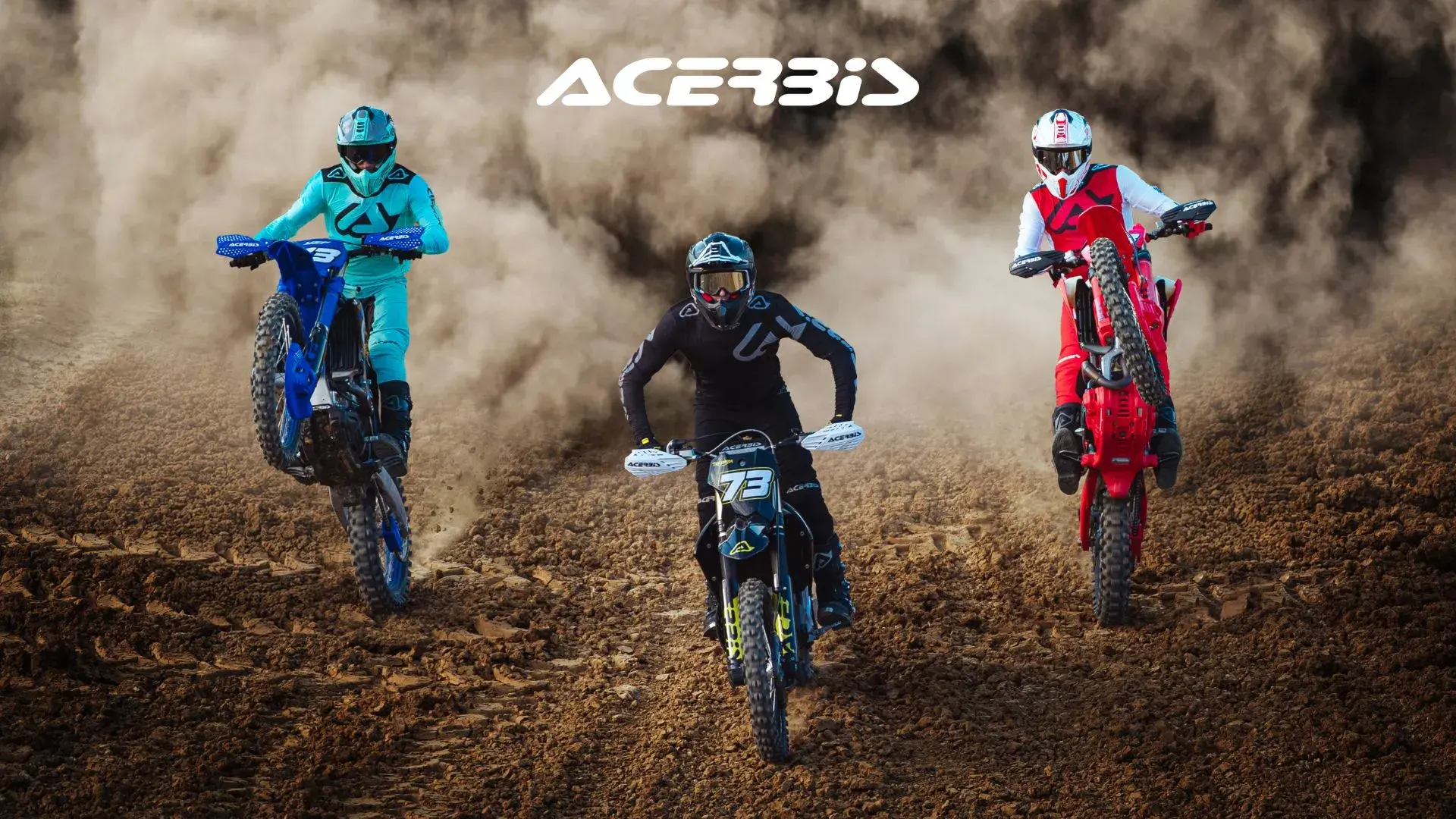 Three motocross riders in full gear (blue, red, black) tear up a dusty dirt track, performing wheelies on their bikes.