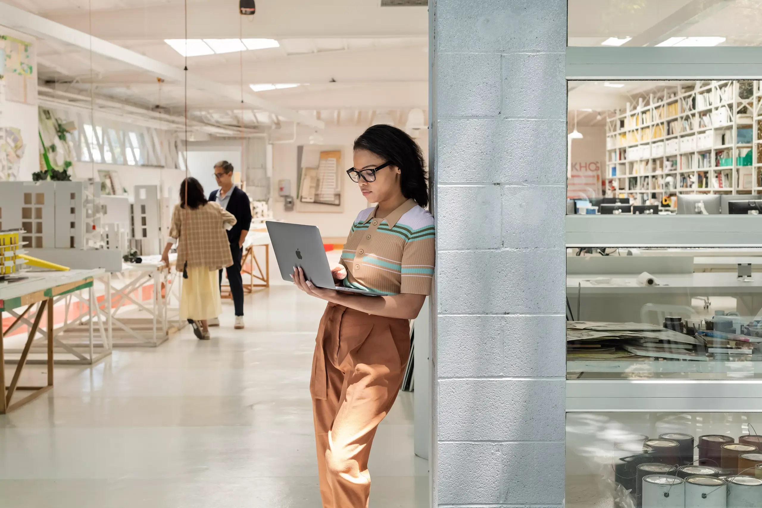 Imagem do cartão de TI: mulher de pé contra uma parede com um notebook