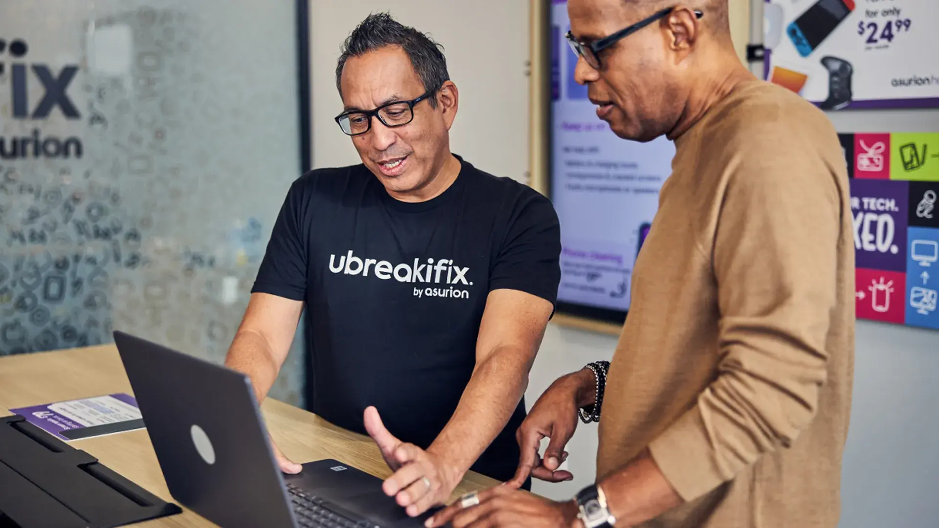 Image for Asana case study featuring customer Asurion. Image features two people looking at a computer in a business environment. 