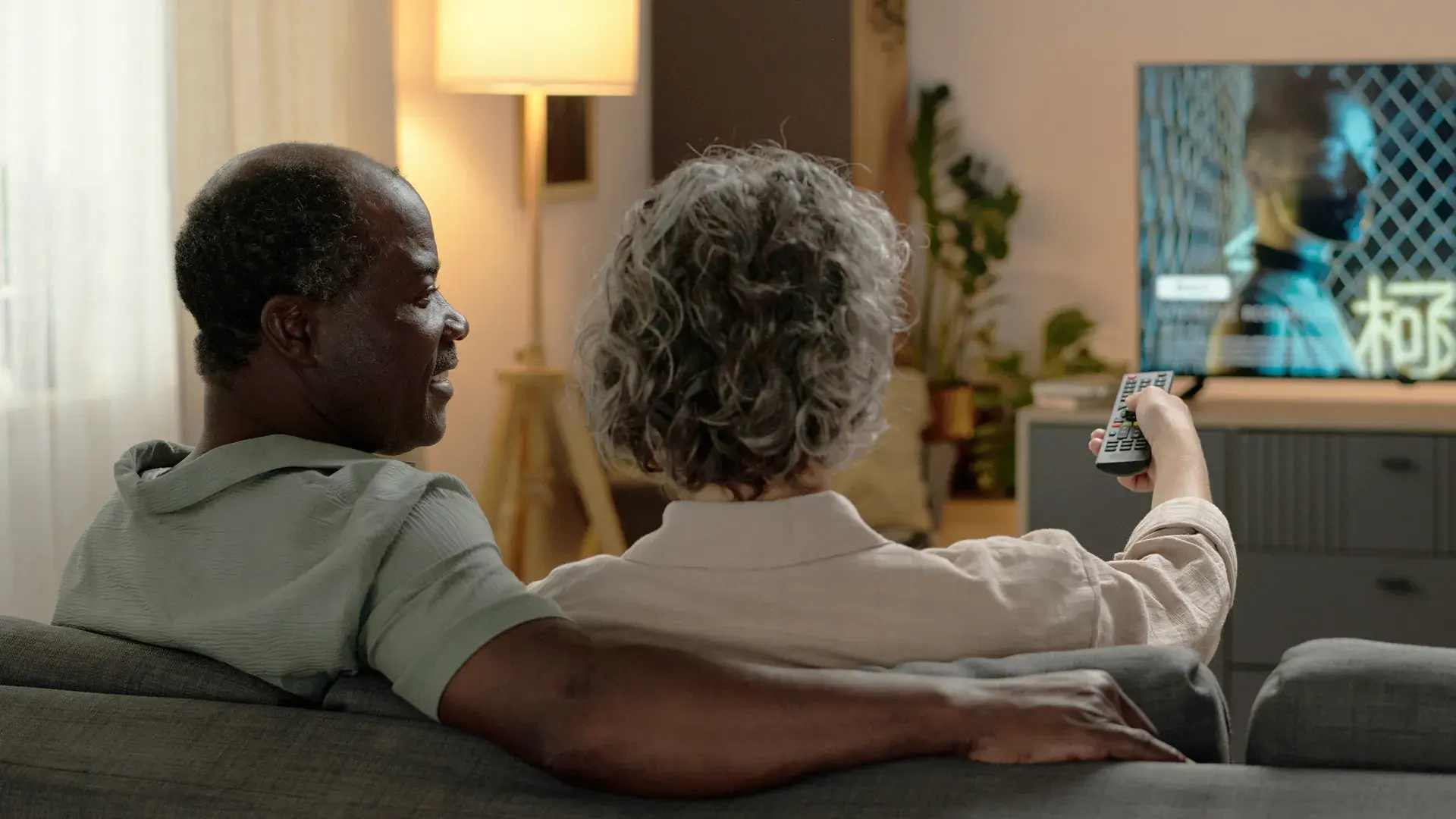 Image of two people sitting on a couch watching DIRECTV