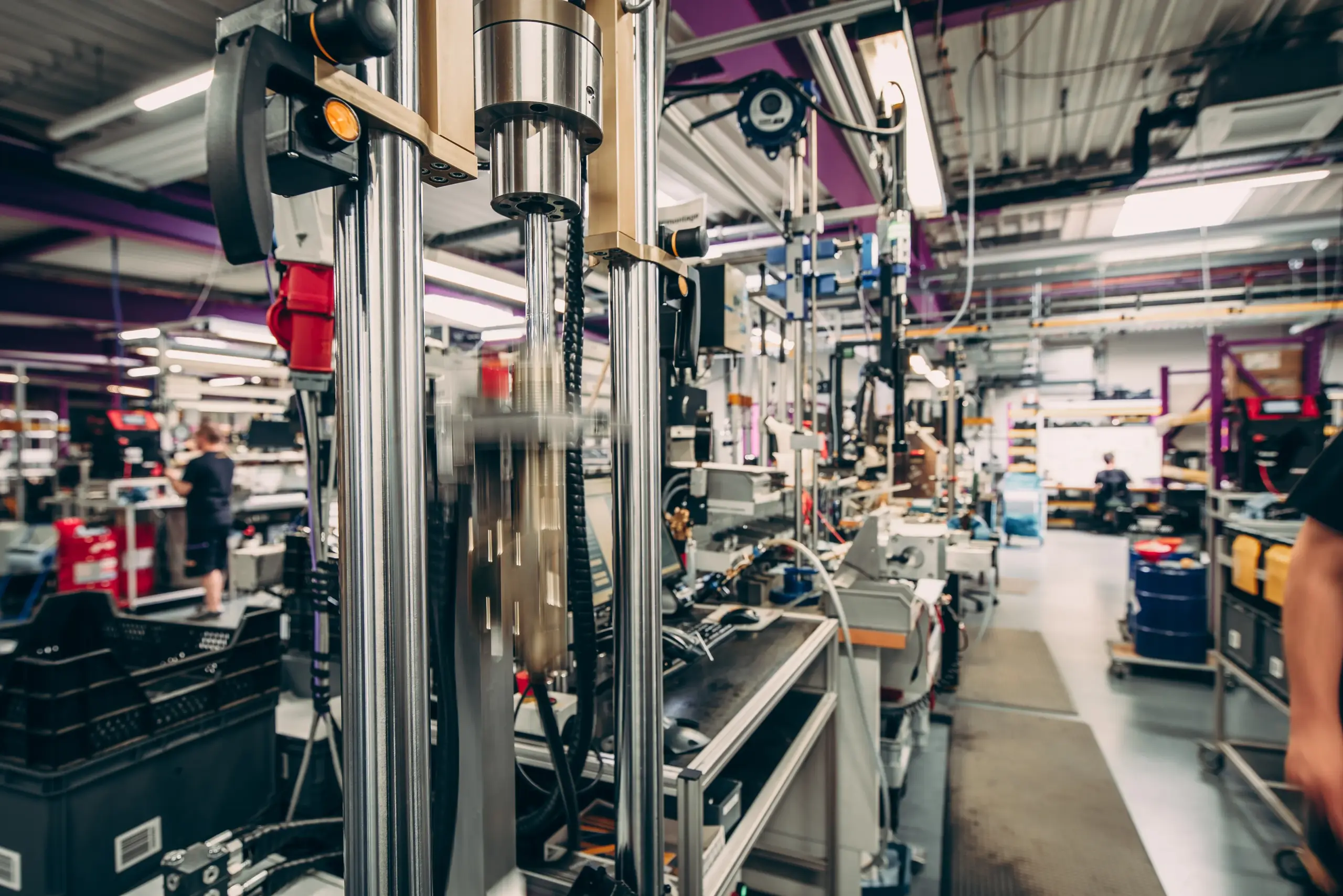 A detailed view of the high-tech production line inside the KW Automotive factory in Fichtenberg. The image shows advanced machinery in operation, illustrating the precise manufacturing process of KW's high-performance suspension components and coilovers.